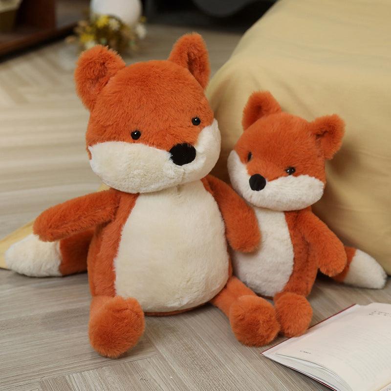 Plush toy set featuring a family of foxes in various sizes, arranged on a cozy bed in a warm and inviting room setting.