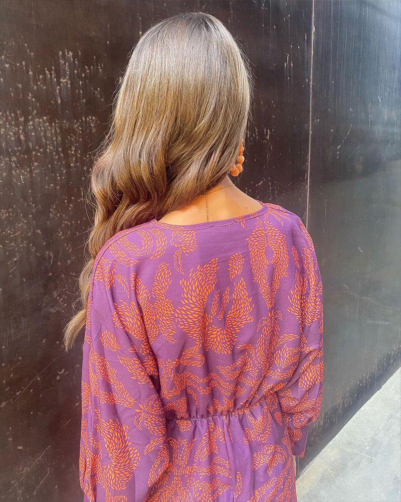 A woman wearing a floral maxi dress with an elegant fit, styled with statement accessories and heels, perfect for formal events or casual outings.