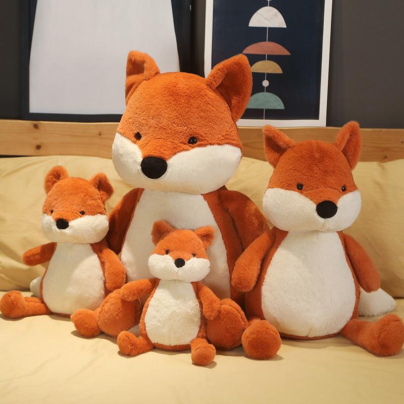Plush toy set featuring a family of foxes in various sizes, arranged on a cozy bed in a warm and inviting room setting.