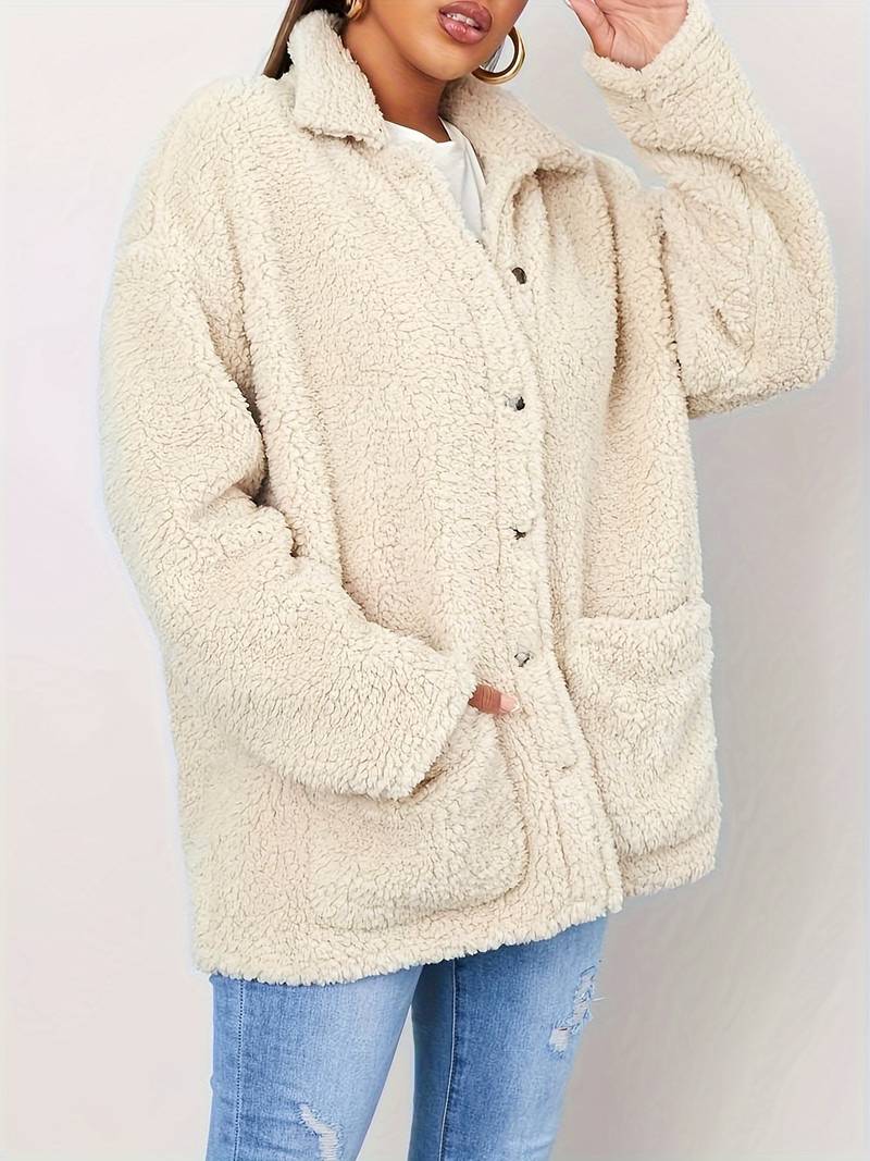 A stylish women's sherpa jacket with a cozy oversized fit, featuring button closures, large front pockets, and a soft textured design, paired with casual jeans and a printed t-shirt for a trendy look.