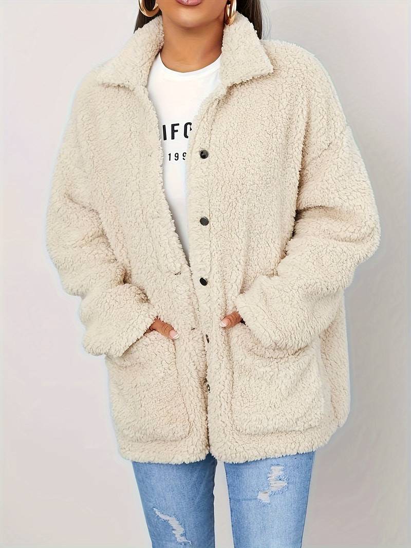 A stylish women's sherpa jacket with a cozy oversized fit, featuring button closures, large front pockets, and a soft textured design, paired with casual jeans and a printed t-shirt for a trendy look.