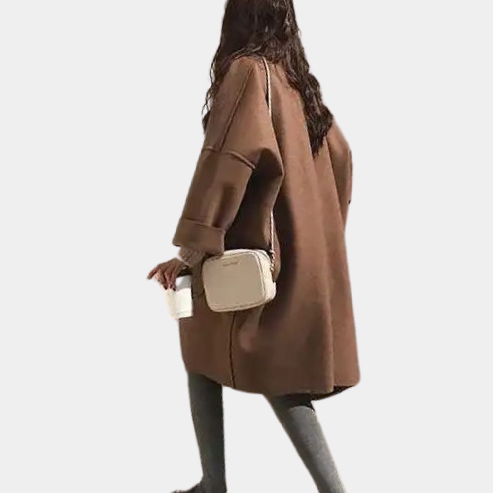 Stylish oversized women's coat with a relaxed fit, featuring deep pockets and a cozy design, worn by a model holding a cup while walking gracefully.