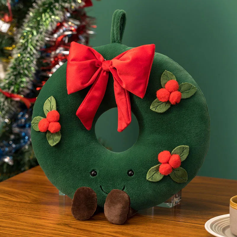 Festive plush toy set featuring a Christmas tree, gingerbread house, wreath, and gingerbread figure, displayed in a cozy holiday-themed setting with wrapped gifts and decorations.