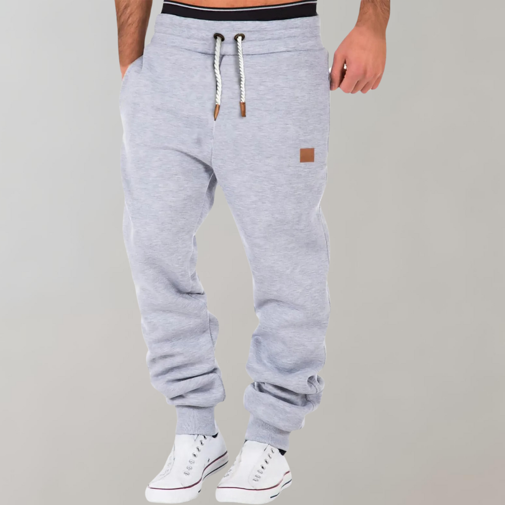 A pair of men's joggers with a relaxed fit, featuring an adjustable drawstring waistband, practical pockets, and a modern design, styled with casual sneakers.