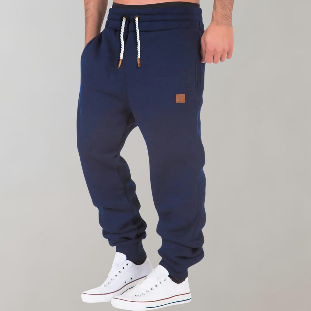 A pair of men's joggers with a relaxed fit, featuring an adjustable drawstring waistband, practical pockets, and a modern design, styled with casual sneakers.