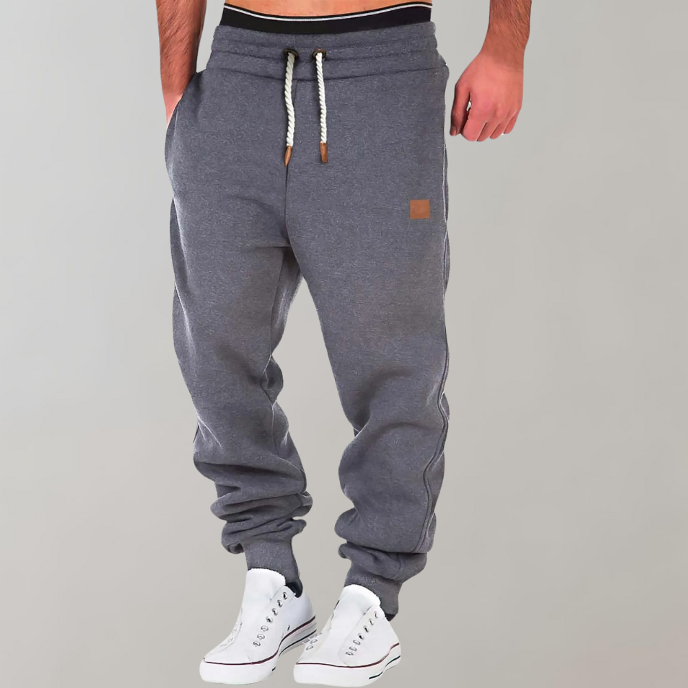 A pair of men's joggers with a relaxed fit, featuring an adjustable drawstring waistband, practical pockets, and a modern design, styled with casual sneakers.