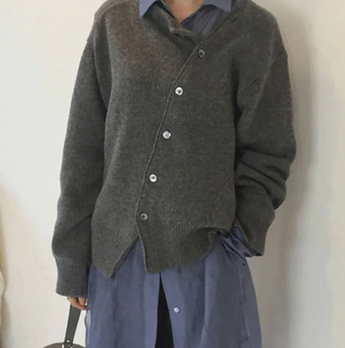 Image of a women's asymmetrical cardigan with a stylish design, featuring button details and a modern cut. Perfect for layering over casual or semi-formal outfits, offering both comfort and a unique fashion statement.