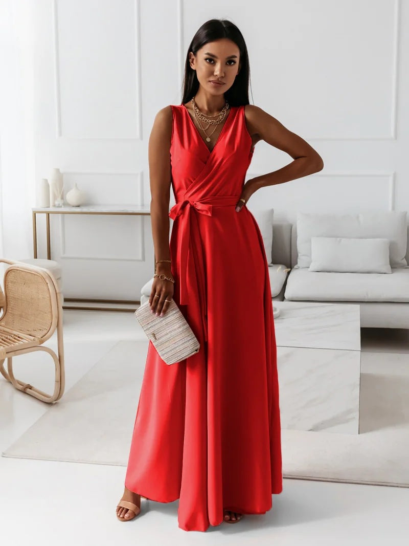 A woman elegantly dressed in a wrap maxi dress featuring a flowing design, styled with minimal accessories, holding a clutch bag, and posing gracefully in a modern living space.