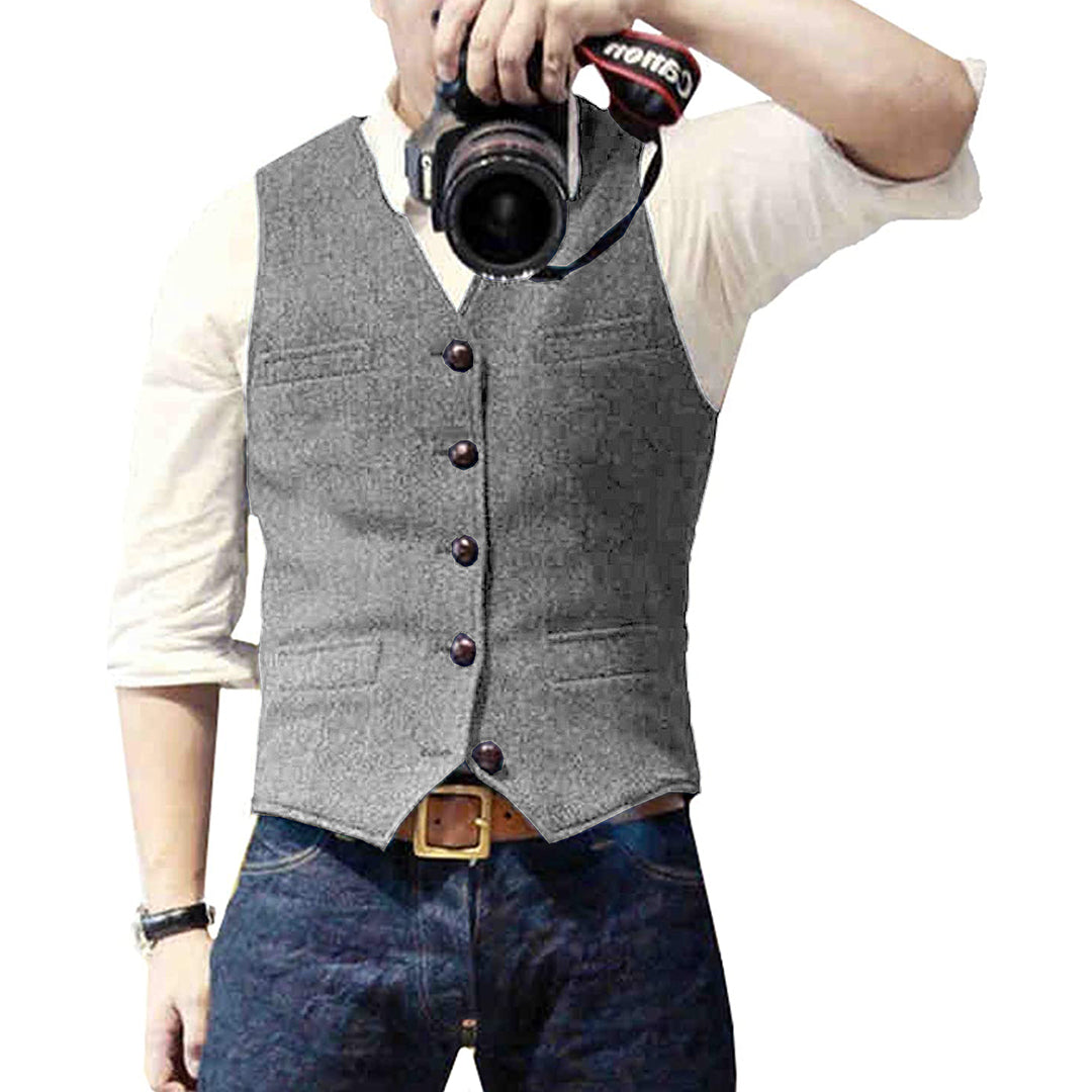 Man wearing a tailored vest paired with a shirt and jeans, holding a camera, showcasing a classic and versatile outfit.