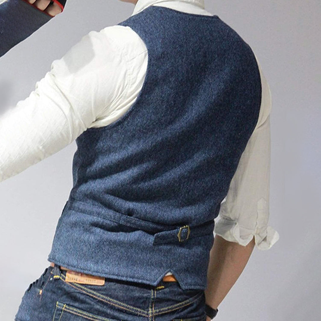 Man wearing a tailored vest paired with a shirt and jeans, holding a camera, showcasing a classic and versatile outfit.