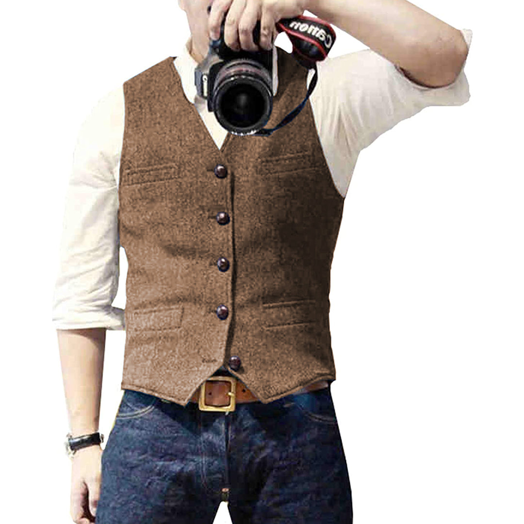 Man wearing a tailored vest paired with a shirt and jeans, holding a camera, showcasing a classic and versatile outfit.