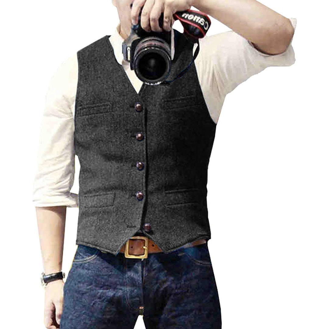 Man wearing a tailored vest paired with a shirt and jeans, holding a camera, showcasing a classic and versatile outfit.