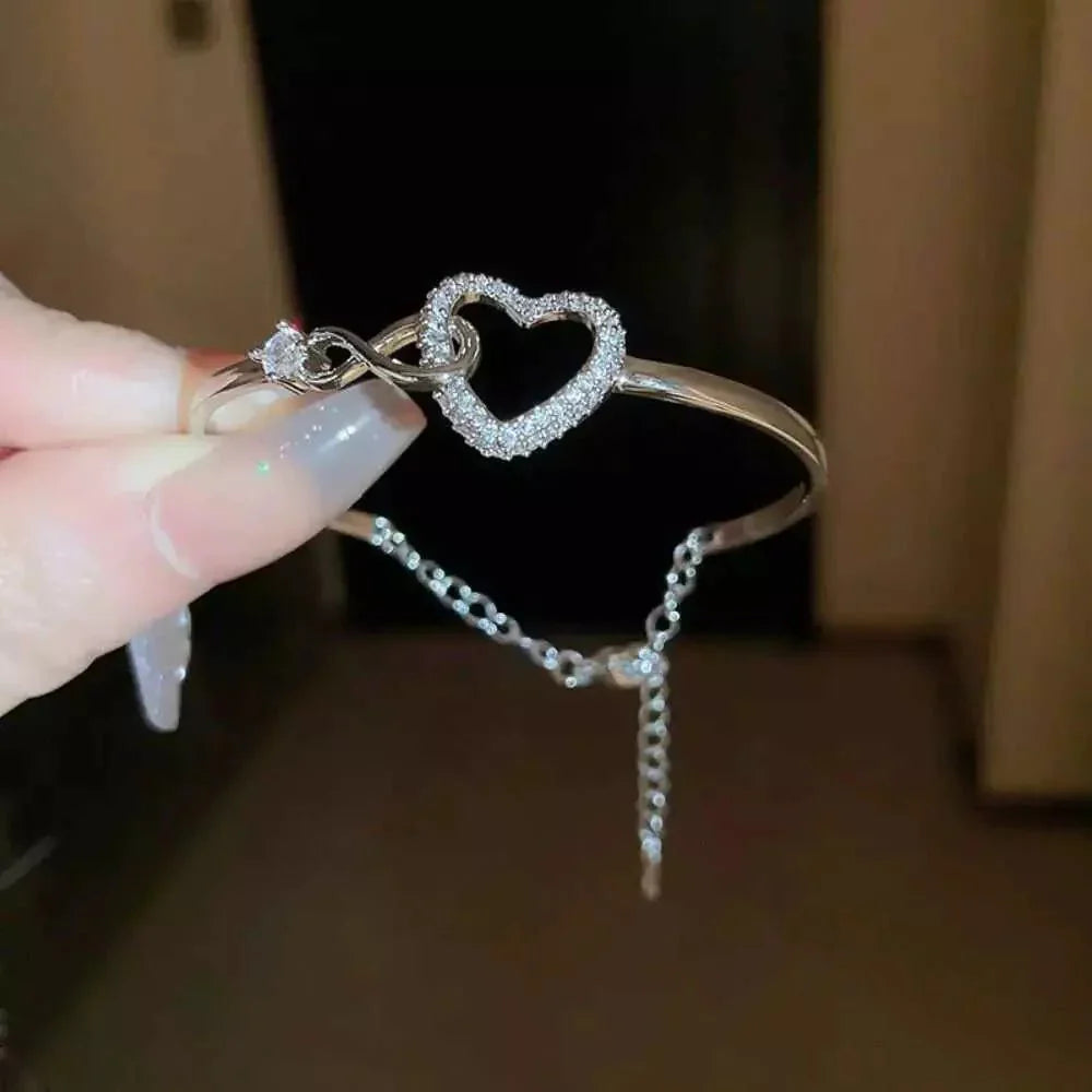 Elegant bracelet with a heart-shaped design and sparkling accents, worn on a wrist to highlight its sophisticated and timeless charm.