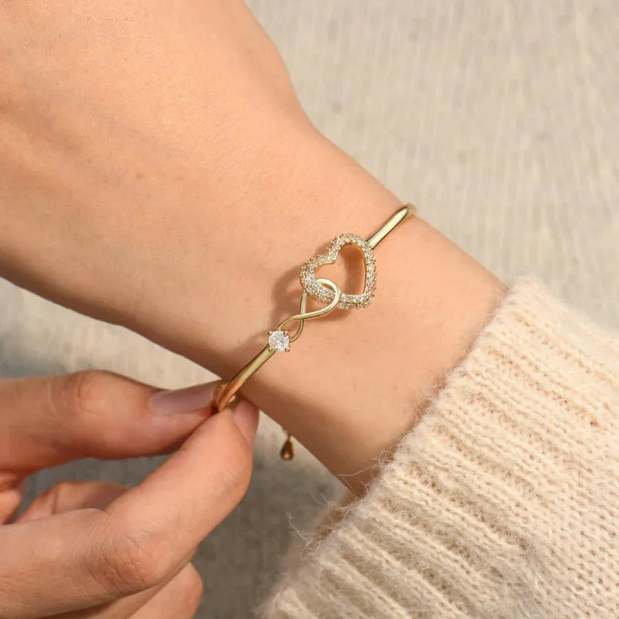 Elegant bracelet with a heart-shaped design and sparkling accents, worn on a wrist to highlight its sophisticated and timeless charm.