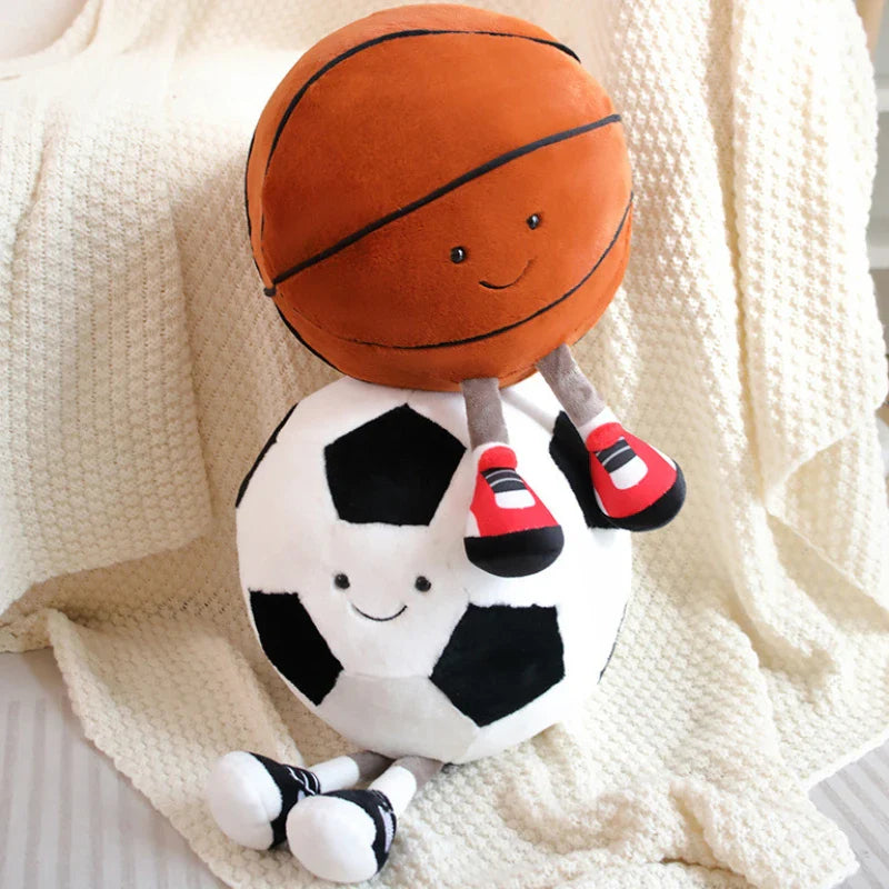 Two playful plush toys designed as cheerful companions, featuring unique sports-inspired designs with smiling faces, seated on a cozy surface.