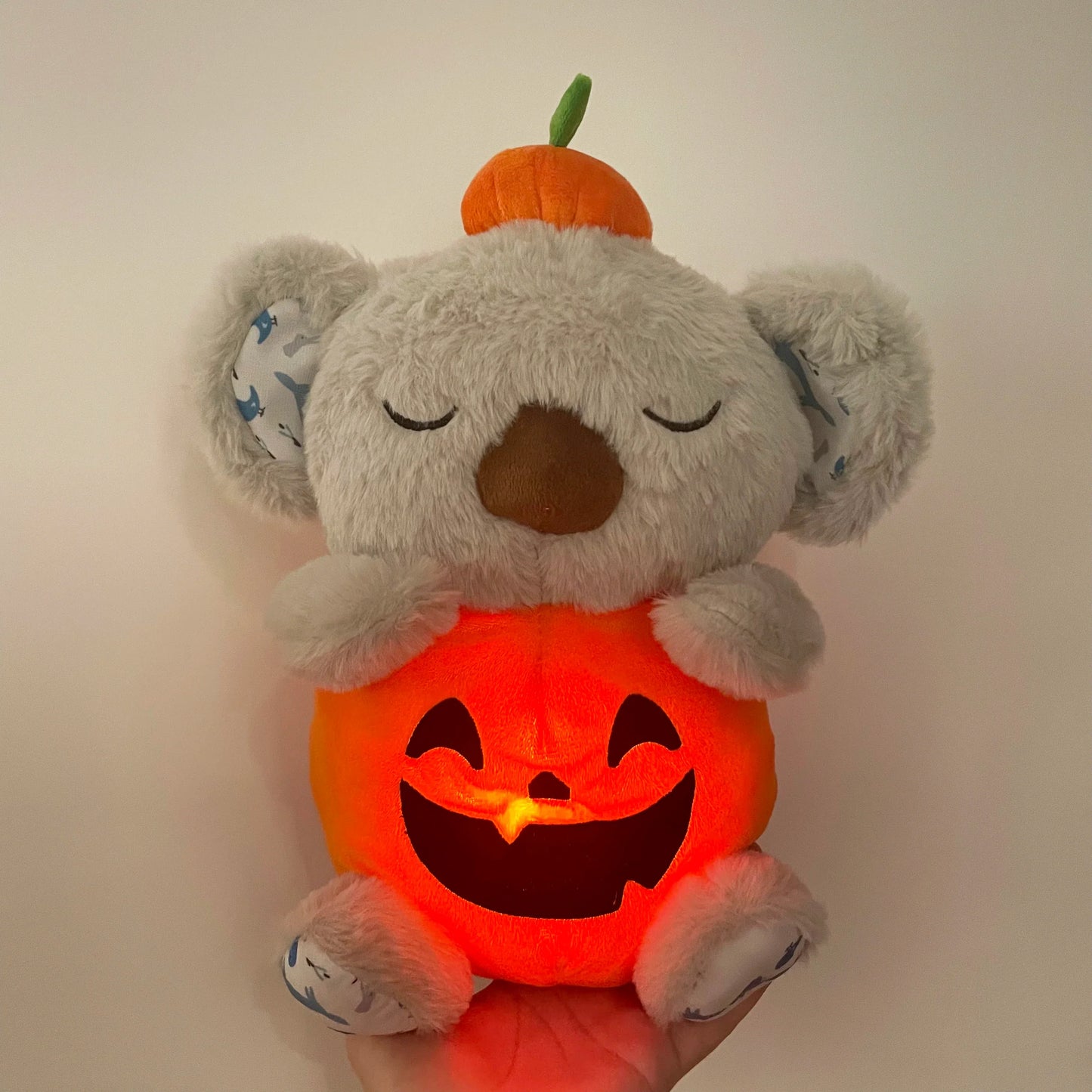 Adorable plush koala toy holding a festive pumpkin with a glowing face, designed to add charm and warmth to any holiday or celebration setting.