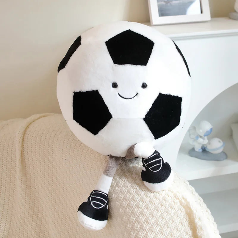 Two playful plush toys designed as cheerful companions, featuring unique sports-inspired designs with smiling faces, seated on a cozy surface.