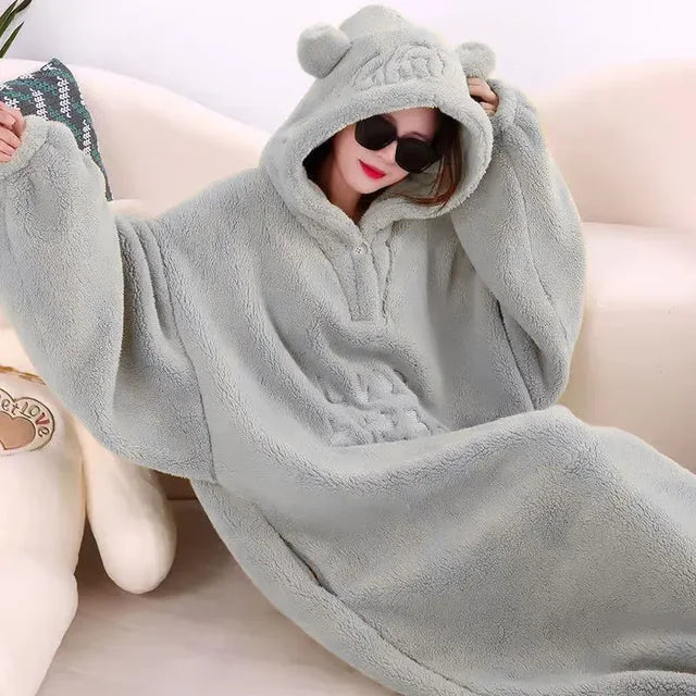A cozy hooded blanket with an oversized design, featuring soft plush material and playful ear details on the hood, perfect for lounging at home and staying warm in style.