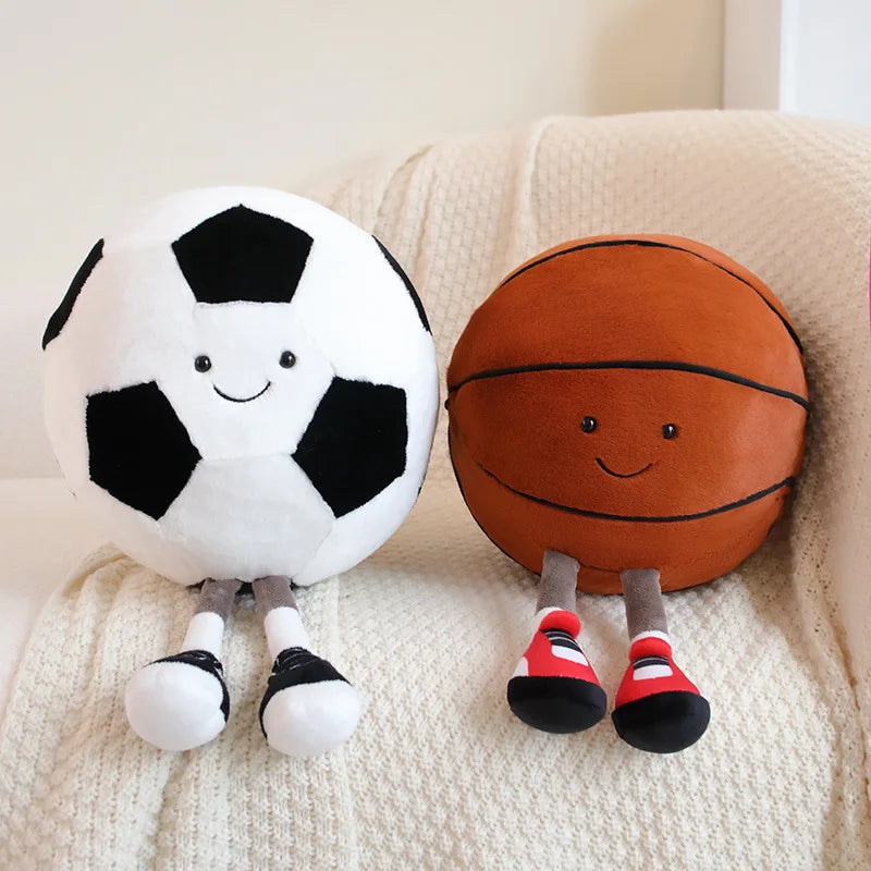 Two playful plush toys designed as cheerful companions, featuring unique sports-inspired designs with smiling faces, seated on a cozy surface.