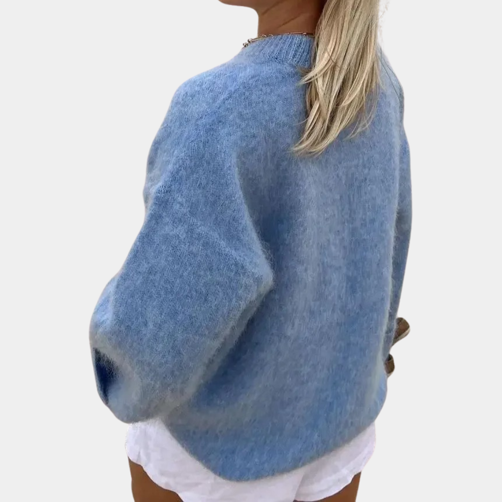 Side view of a woman wearing a relaxed fit knit sweater paired with shorts, showcasing the comfortable and cozy design of the sweater.