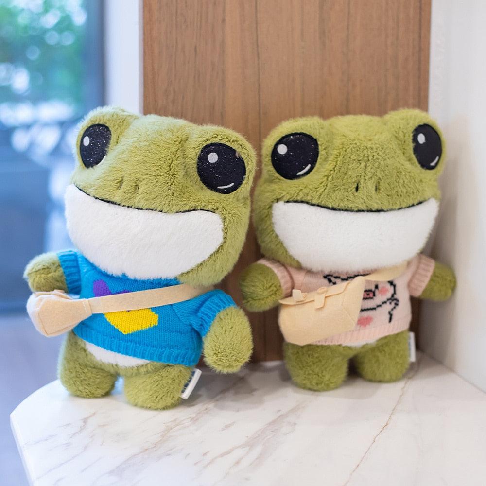 Adorable plush frog toy with a charming design, featuring a small bag and decorative details, placed on a wooden surface.