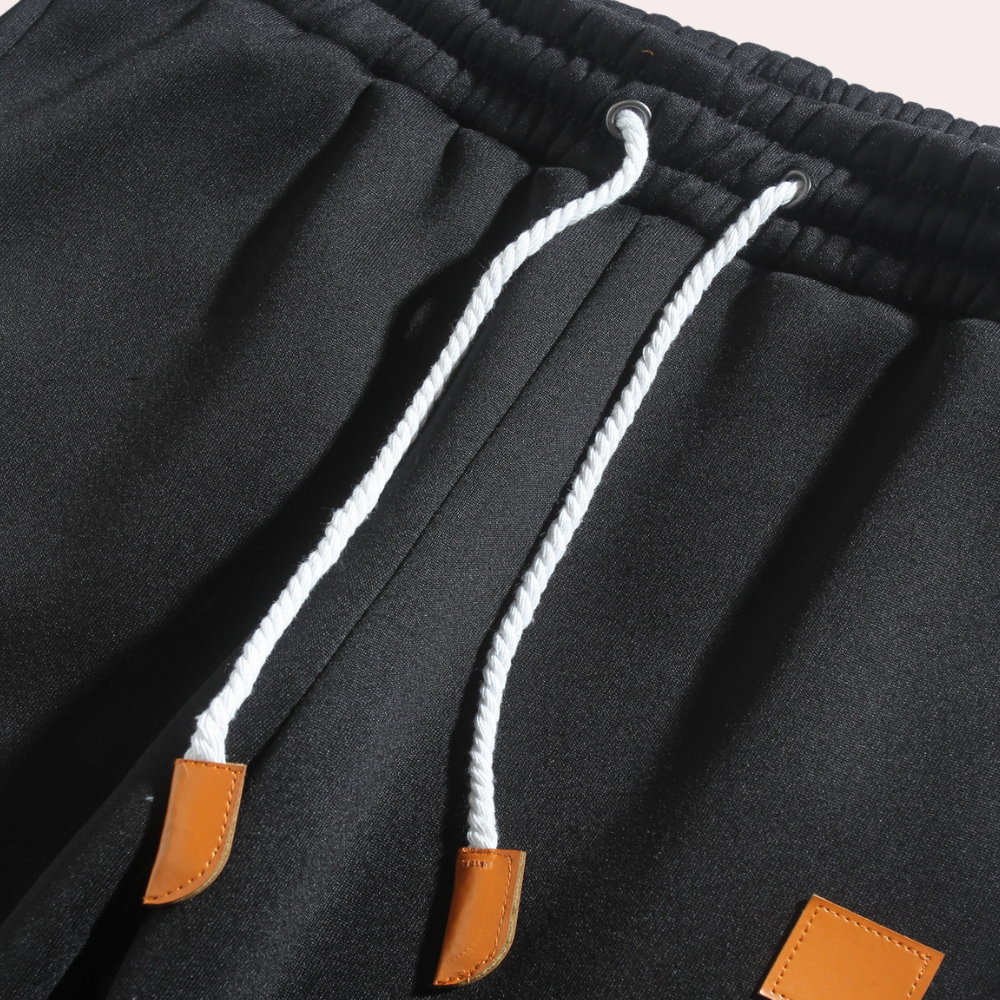 A pair of men's joggers with a relaxed fit, featuring an adjustable drawstring waistband, practical pockets, and a modern design, styled with casual sneakers.