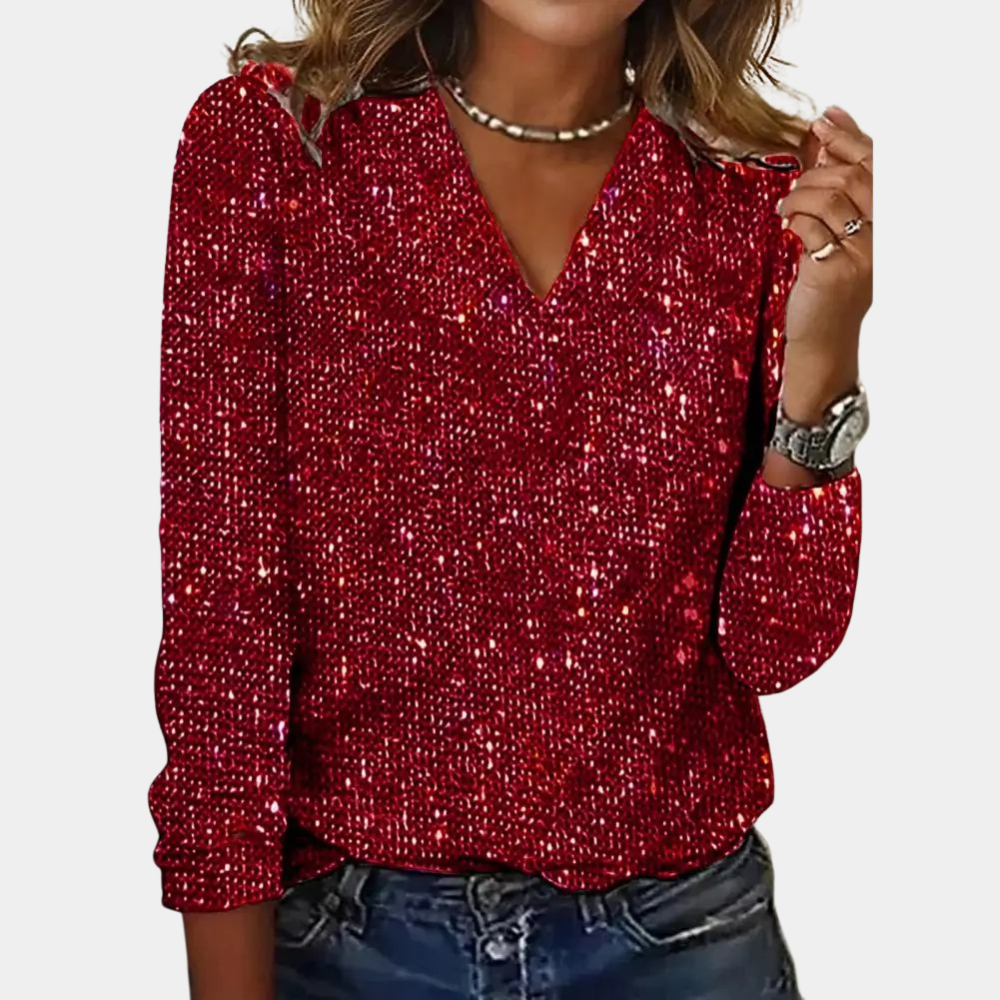 A woman wearing a sparkling V-neck blouse with an elegant shine, styled with casual jeans and accessorized with a necklace and bracelets.