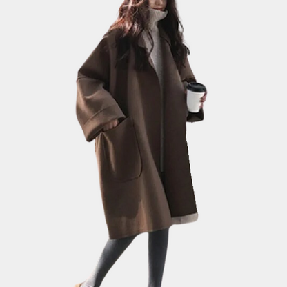 Stylish oversized women's coat with a relaxed fit, featuring deep pockets and a cozy design, worn by a model holding a cup while walking gracefully.