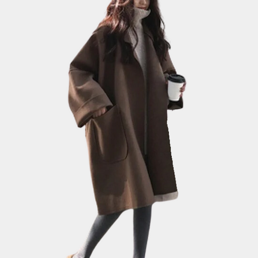 Stylish oversized women's coat with a relaxed fit, featuring deep pockets and a cozy design, worn by a model holding a cup while walking gracefully.