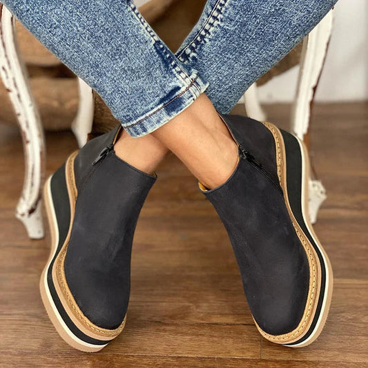  Stylish women's ankle boots with a modern design and zipper closure, displayed on a wooden floor. Perfect for casual or everyday wear.