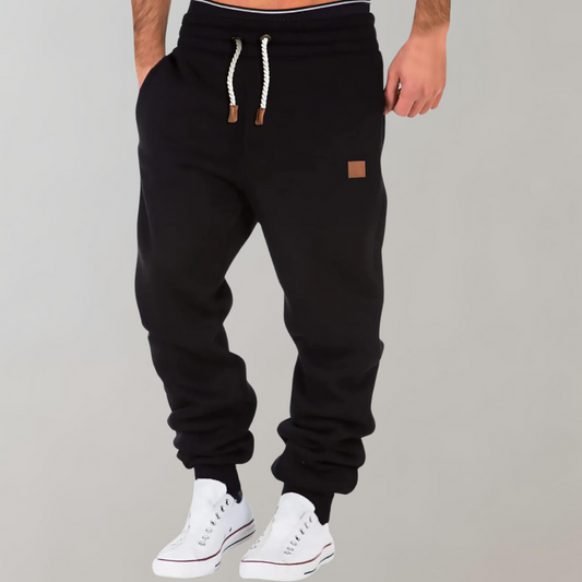A pair of men's joggers with a relaxed fit, featuring an adjustable drawstring waistband, practical pockets, and a modern design, styled with casual sneakers.