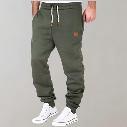 A pair of men's joggers with a relaxed fit, featuring an adjustable drawstring waistband, practical pockets, and a modern design, styled with casual sneakers.