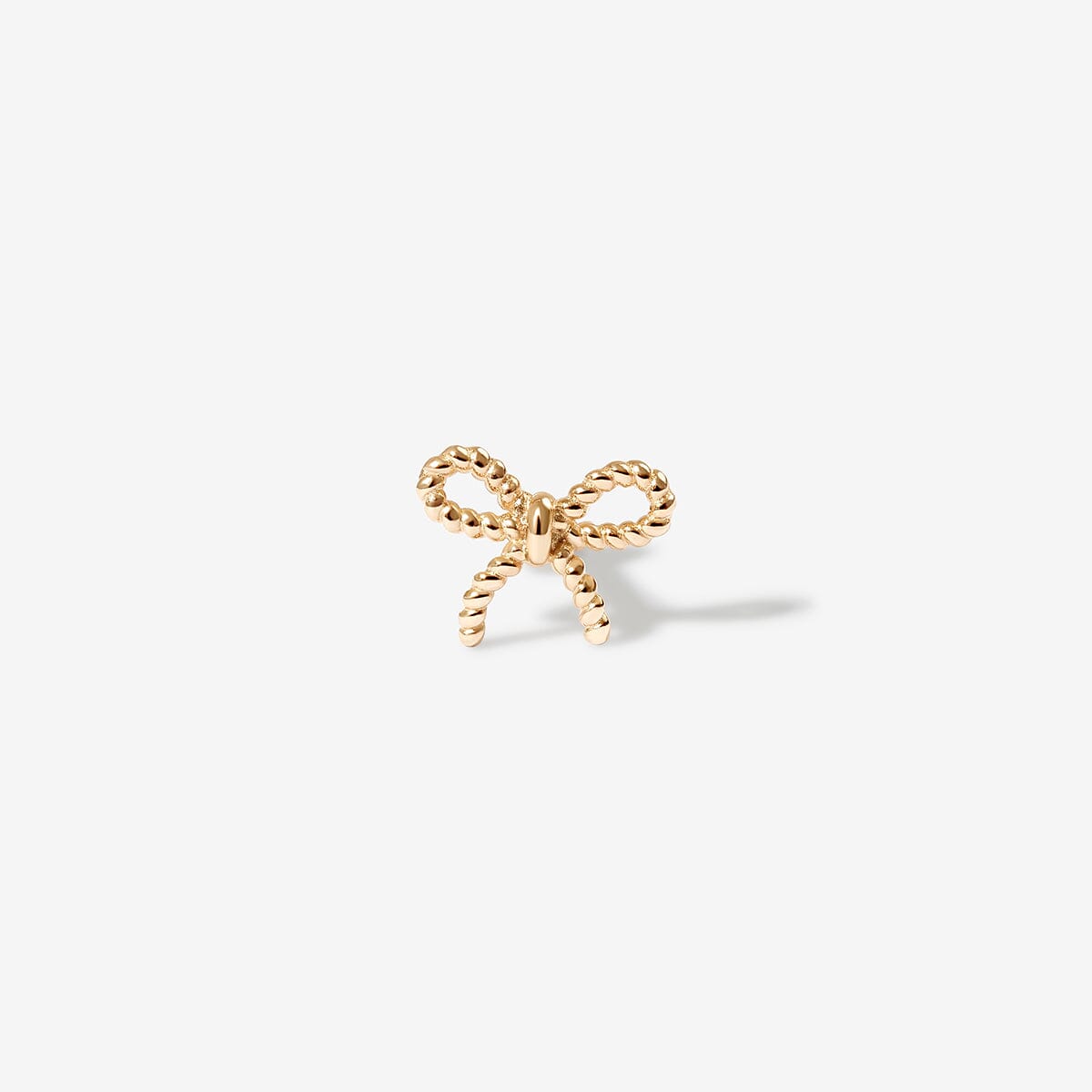 Close-up of a woman's ear adorned with delicate bow-shaped earrings, styled with a ribbon in her hair for an elegant and feminine look.