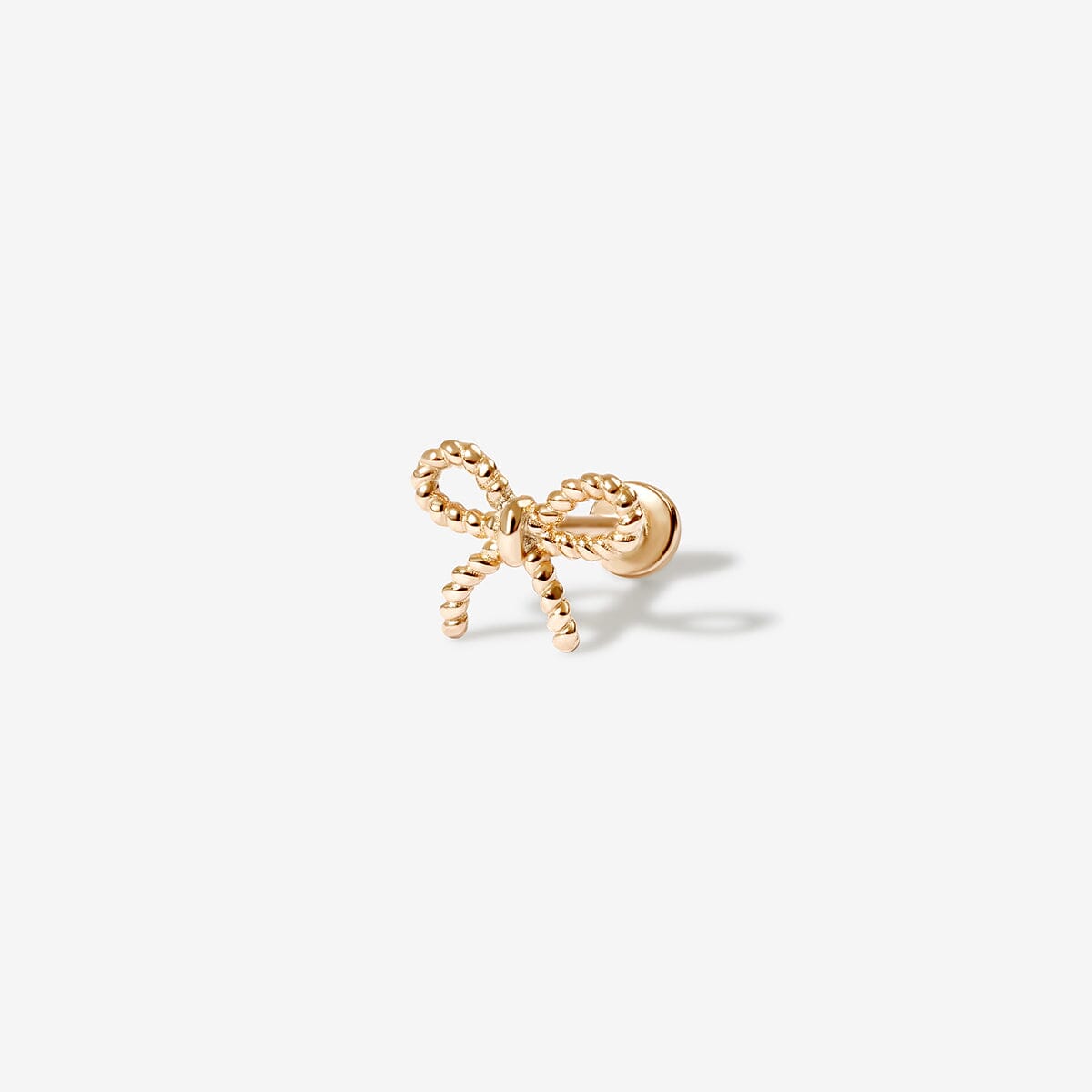 Close-up of a woman's ear adorned with delicate bow-shaped earrings, styled with a ribbon in her hair for an elegant and feminine look.