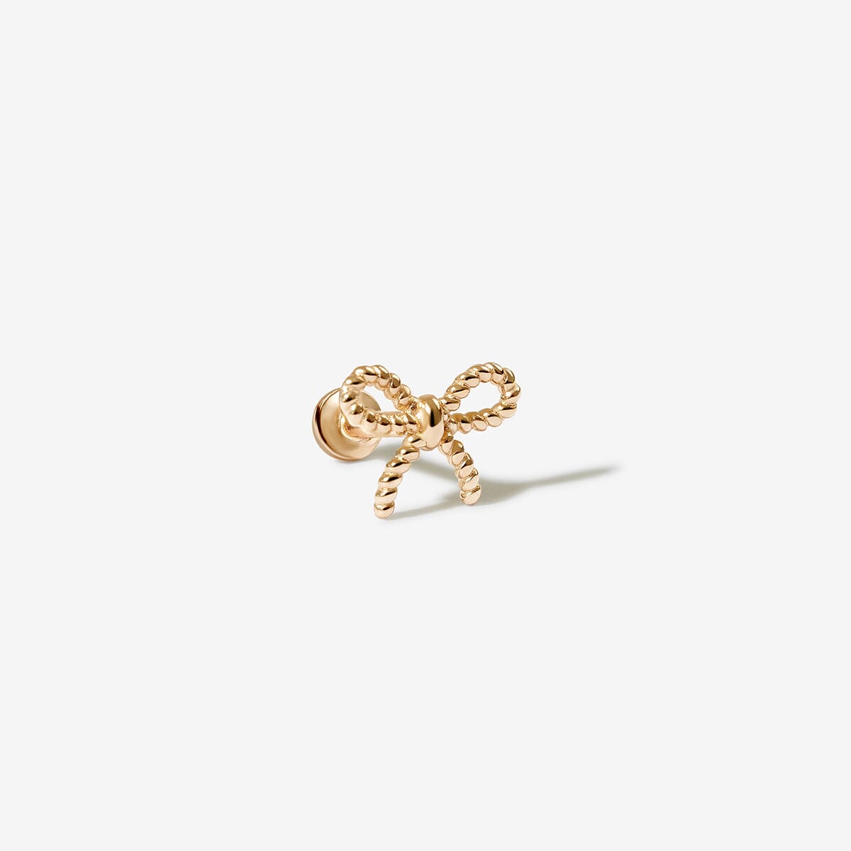Close-up of a woman's ear adorned with delicate bow-shaped earrings, styled with a ribbon in her hair for an elegant and feminine look.