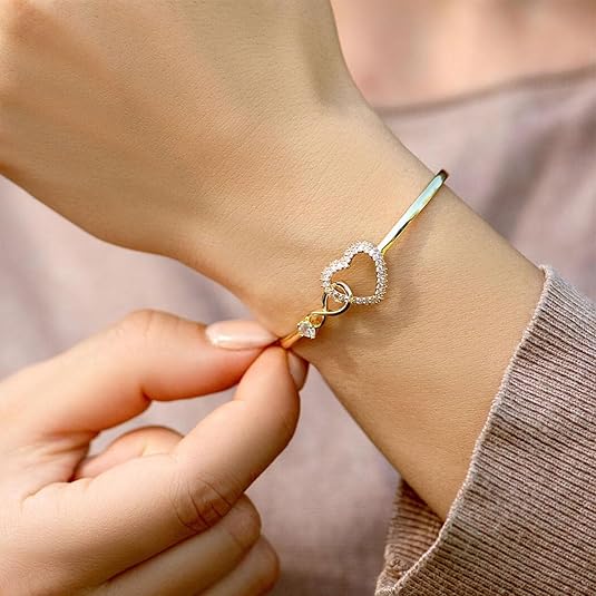 Elegant bracelet with a heart-shaped design and sparkling accents, worn on a wrist to highlight its sophisticated and timeless charm.