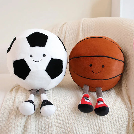 Two playful plush toys designed as cheerful companions, featuring unique sports-inspired designs with smiling faces, seated on a cozy surface.