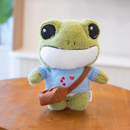 Adorable plush frog toy with a charming design, featuring a small bag and decorative details, placed on a wooden surface.