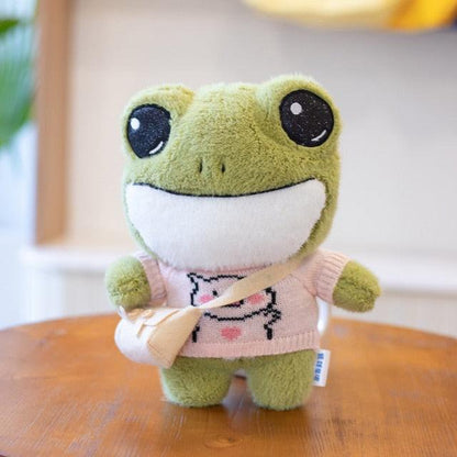 Adorable plush frog toy with a charming design, featuring a small bag and decorative details, placed on a wooden surface.